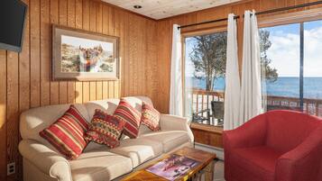 Una habitación con paneles de madera, un sofá, un sillón rojo, una mesita de centro y un cuadro en la pared.