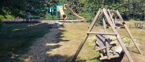 A playground with a slide and swings in a park.