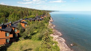 A coastal property with multiple wooden houses along a rocky shoreline, surrounded by dense forest. - Lutsen Sea Villas (Lutsen)
