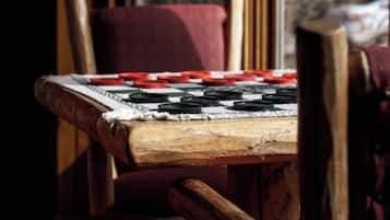 Primer plano de una mesa de madera con un mantel a cuadros, mostrando fichas de juego en negro y rojo.