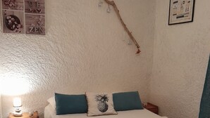 Una camera da letto con un letto, cuscini, un comodino, una lampada e una parete decorata con opere d'arte.