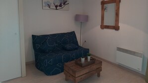 Et værelse med sofa, lampe, spejl og et lille bord med dekorative genstande.
