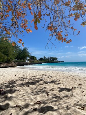 A beach with clear skies, waves, and a distant shoreline.