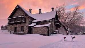 A stone cabin with a balcony, surrounded by snow.