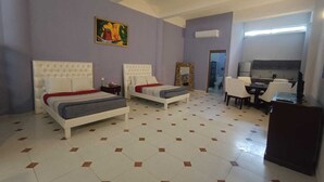A hotel room with two beds, a desk, a chair, a television, and a bathroom visible through an open door. - Amplio estudio en Cozumel, frente al mar E12 (San Miguel de Cozumel)