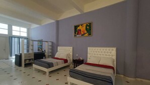 A bedroom with two beds, a desk, and a large window. - Amplio estudio en Cozumel, frente al mar E12 (San Miguel de Cozumel)