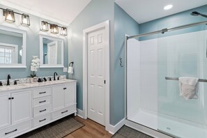 Une salle de bain avec une douche à parois de verre, un meuble-lavabo blanc avec un miroir et un évier.