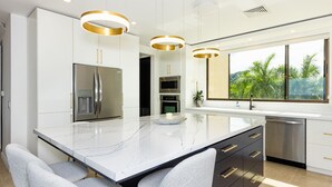 Una cocina moderna con una isla grande, electrodomésticos de acero inoxidable y vistas al exterior.