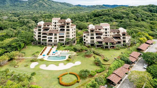 Un resort con varias construcciones, piscina y abundante vegetación.