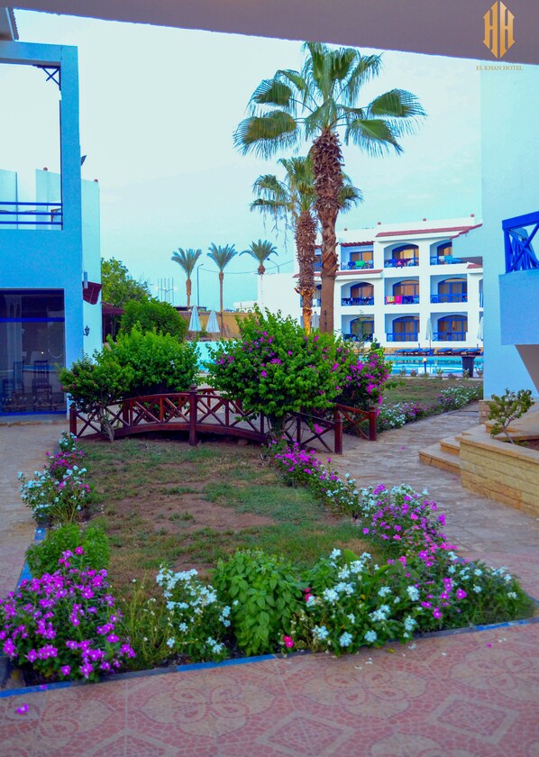 Un patio de hotel con palmeras, piscina y un puente.