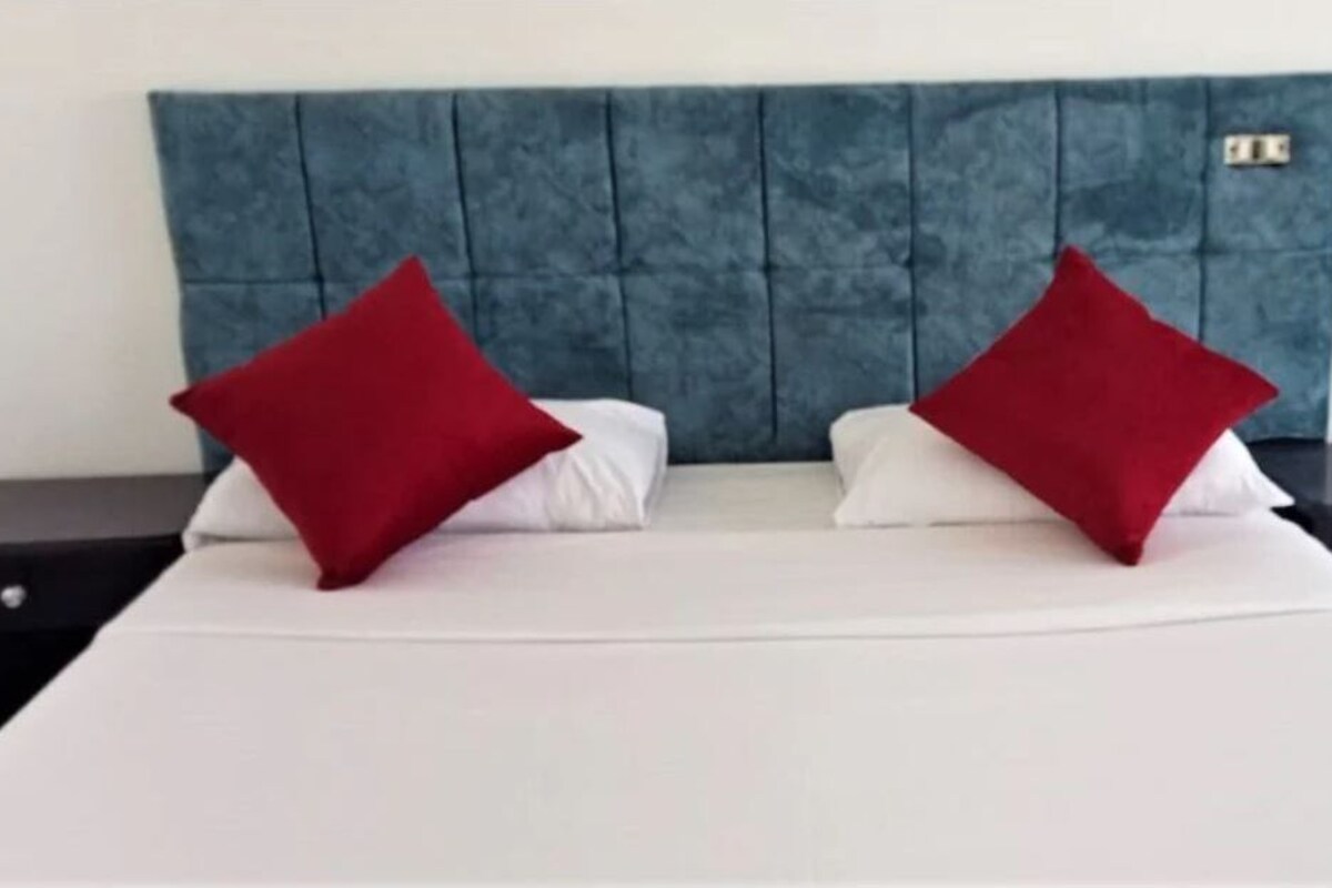 A bed with a blue headboard, two white pillows, and two red pillows.