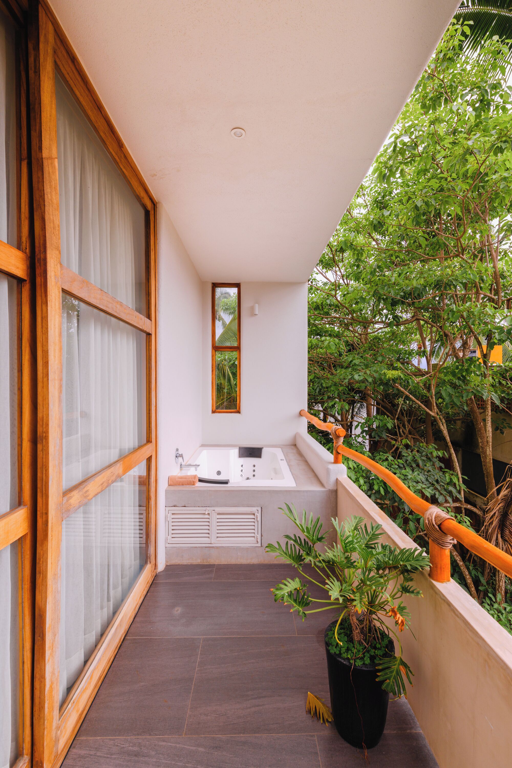 Un balcon doté d’un évier et d’un miroir, de plantes en pot et offrant une vue sur la verdure.