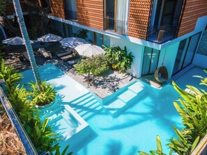 A modern outdoor pool area with a clear blue pool, surrounded by lush greenery and a few lounge chairs. - Agua de Luna Boutique Hotel, San Pancho Nayarit (San Francisco)