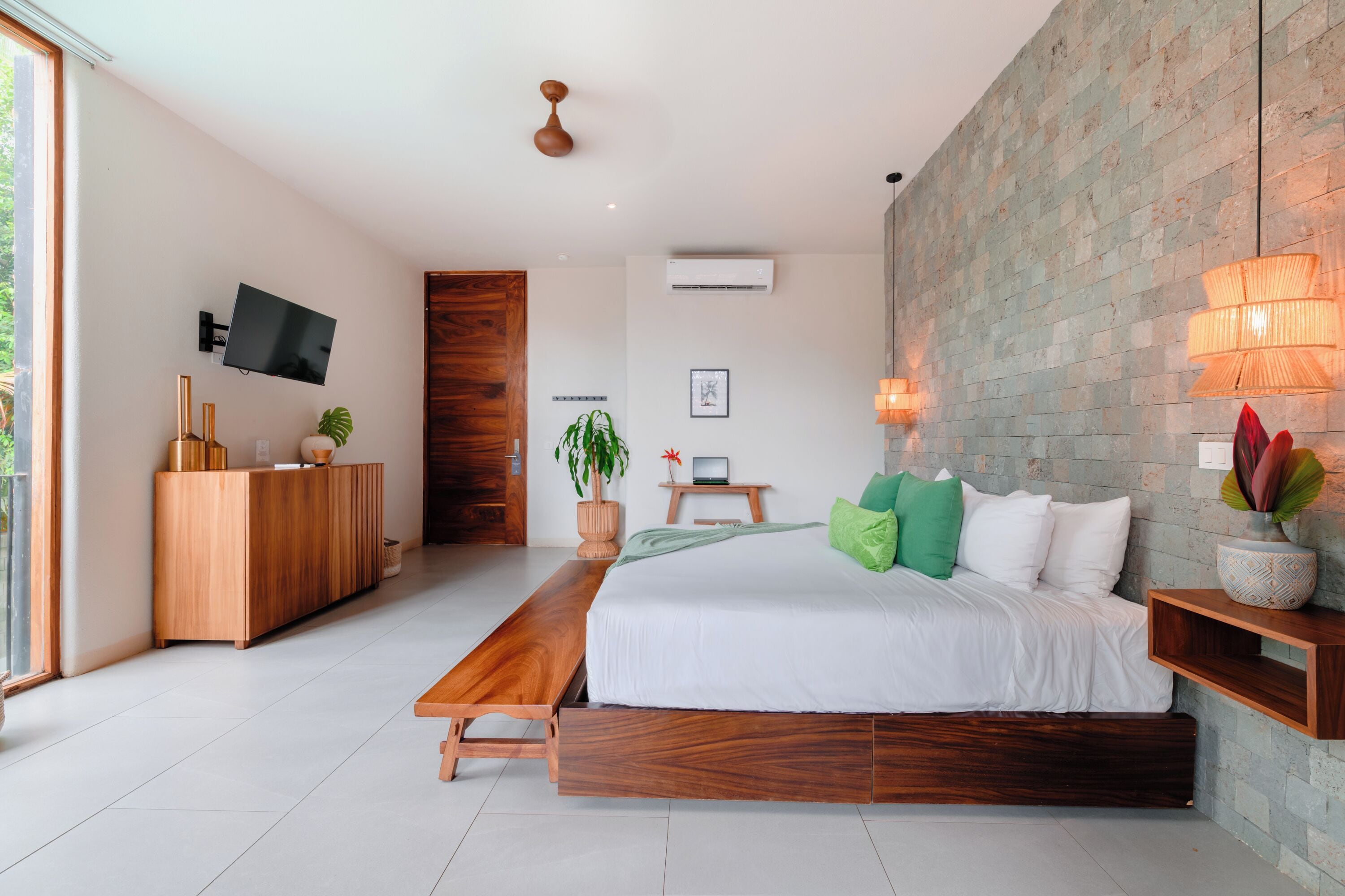 A modern bedroom with a large bed, wooden bench, desk, and TV.
