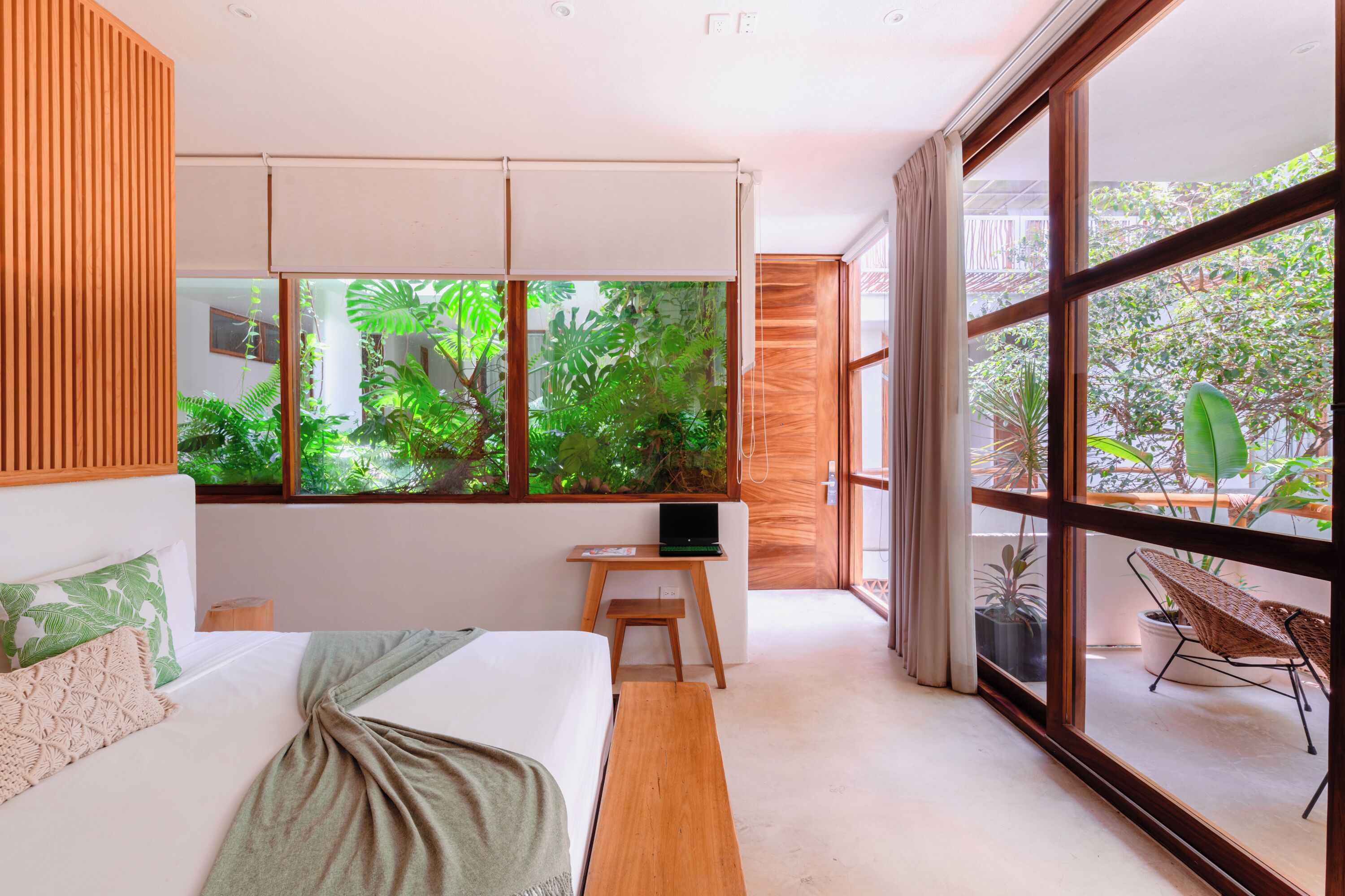 A modern bedroom with a large window, a bed, a desk, and a chair.
