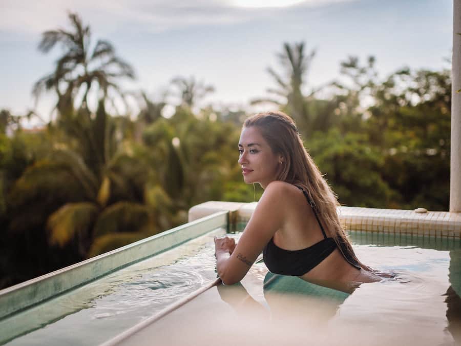 A person in a swimming pool with a view of tropical vegetation.