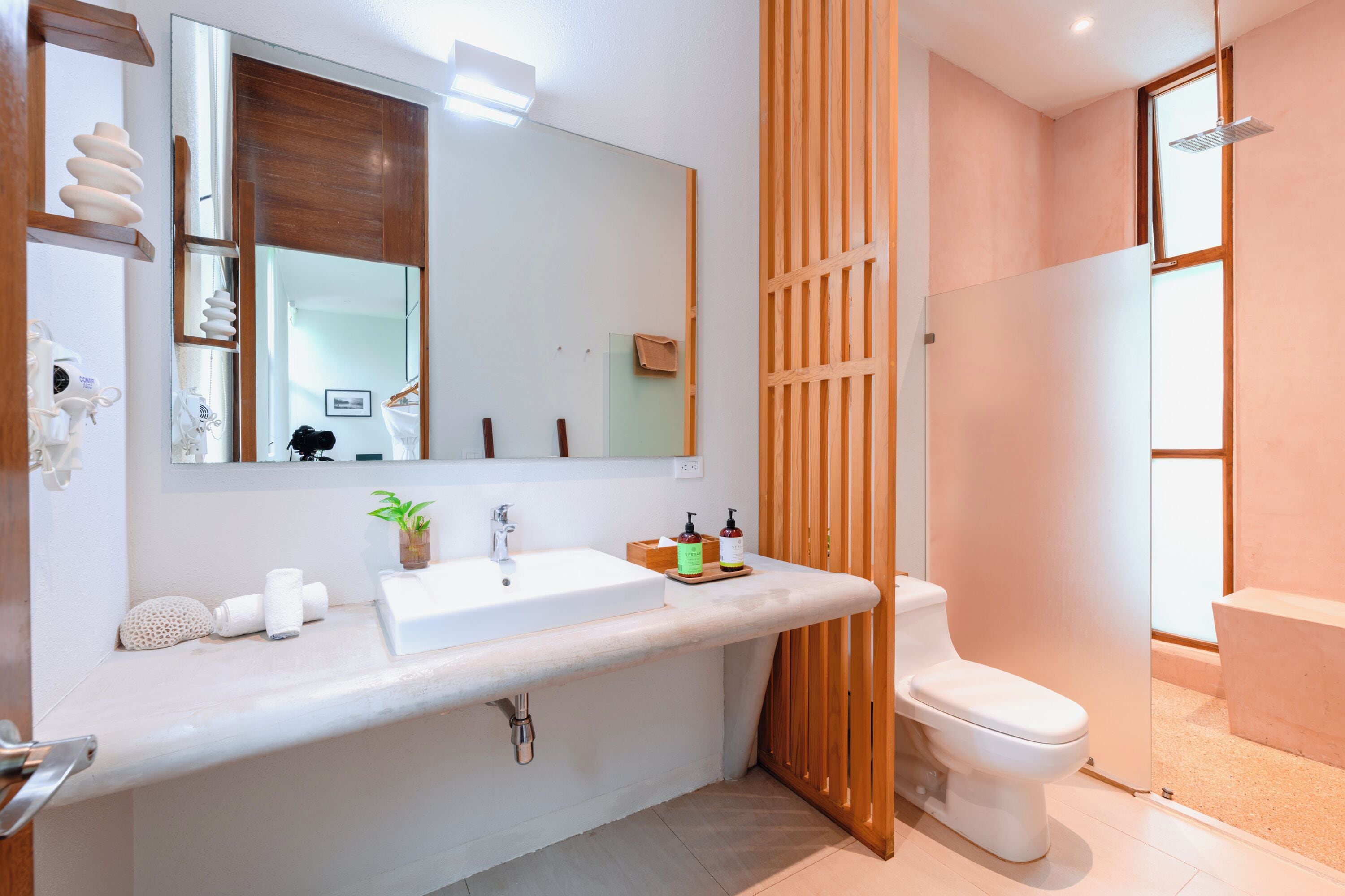 A modern bathroom with a large mirror, white sink, and toilet.
