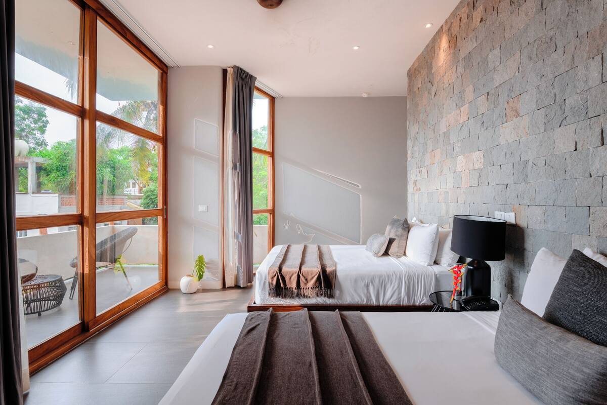 Una habitación de hotel moderna con una cama grande, un sofá, un escritorio y una pared de piedra.