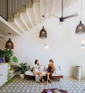 Una sala de estar moderna con un sofá, dos lámparas colgantes y un ventilador de techo.
