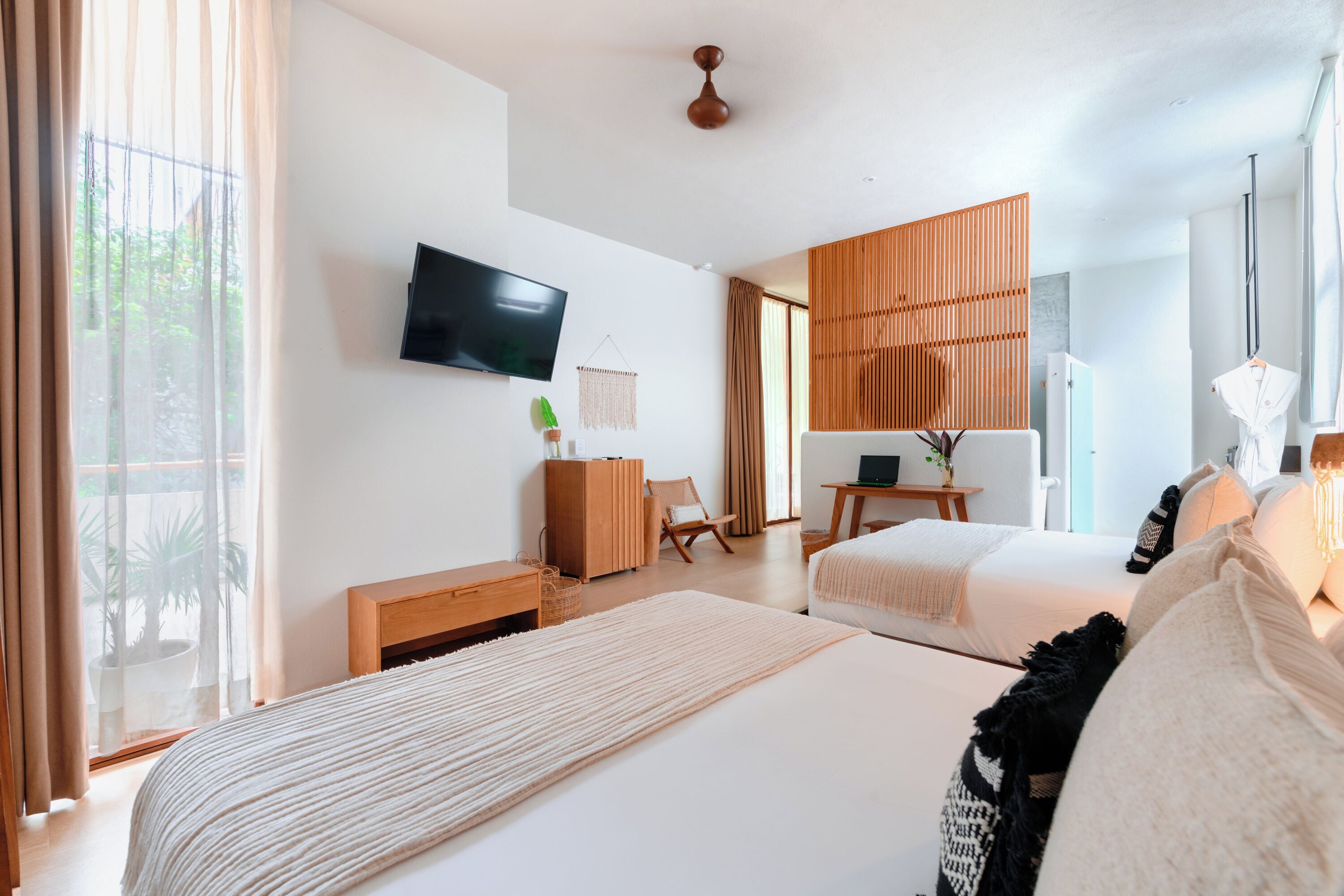Quarto de hotel moderno com uma cama grande, escrivaninha, cadeira, televisão e vista para o exterior.