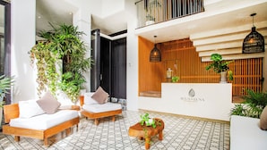 Eine Hotelhalle mit Rezeption, einer Sitzecke mit Sofas und einem gefliesten Boden.
