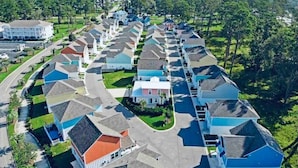 Zona residencial amb diverses cases alineades, una carretera central i espais verds.