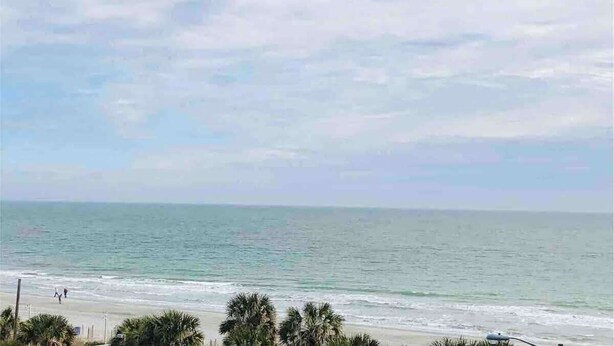 Una platja amb cel blau i mar tranquil·la.
