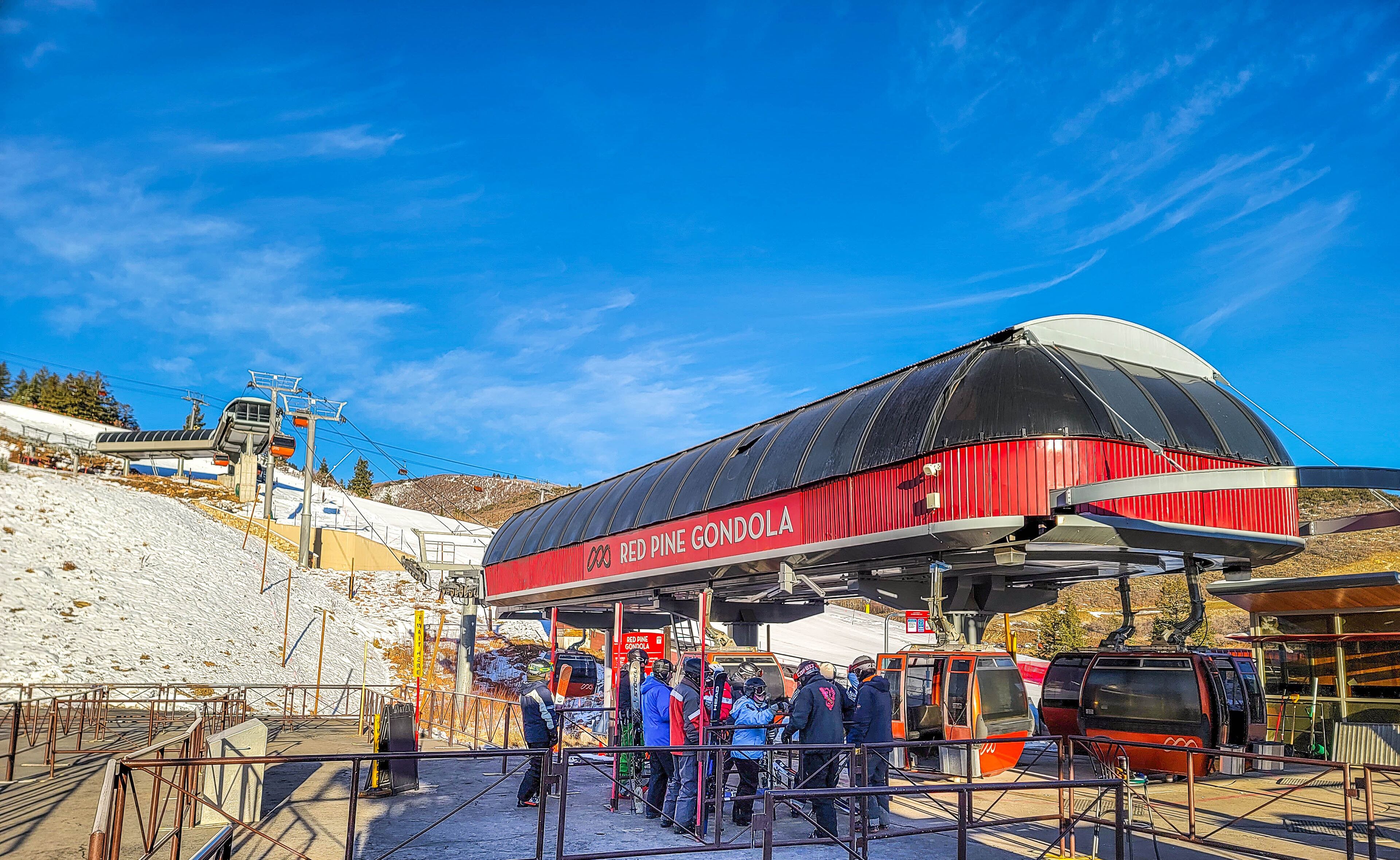 Een liftstation voor een skilift met een gondel genaamd "Red Pine Gondola" en een besneeuwde helling op de achtergrond.