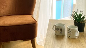 A room with a brown sofa, a wooden table with two white mugs, and a potted plant. - Airport İnalens Konaklama (Arnavutköy)