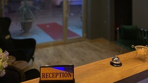 A reception area with a sign labeled "RECEPTION," a wooden reception desk, and pendant lighting. - Airport İnalens Konaklama (Arnavutköy)