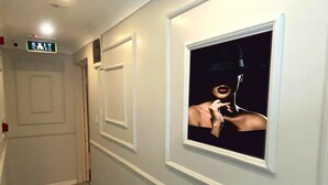 A hallway with an exit sign, a door, and a framed picture on the wall. - Airport İnalens Konaklama (Arnavutköy)