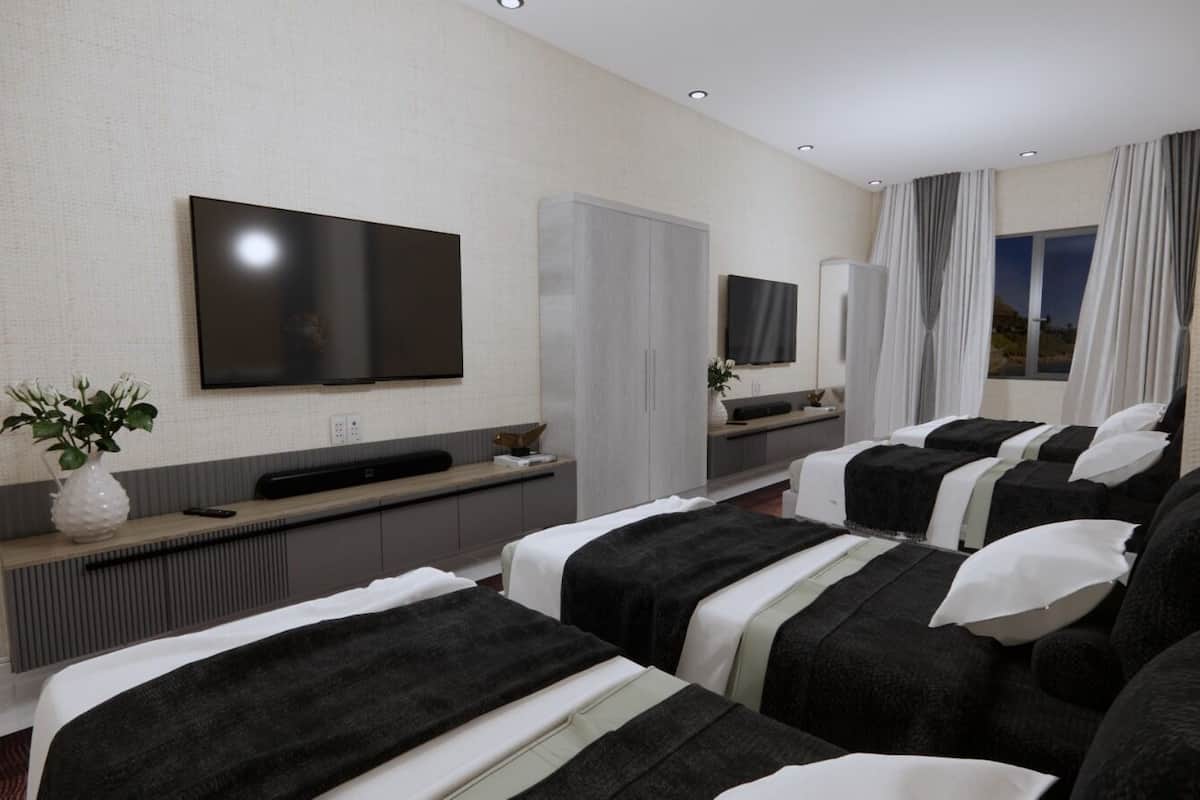Une chambre d’hôtel avec deux lits, une télévision, un minibar et une grande fenêtre avec des rideaux.