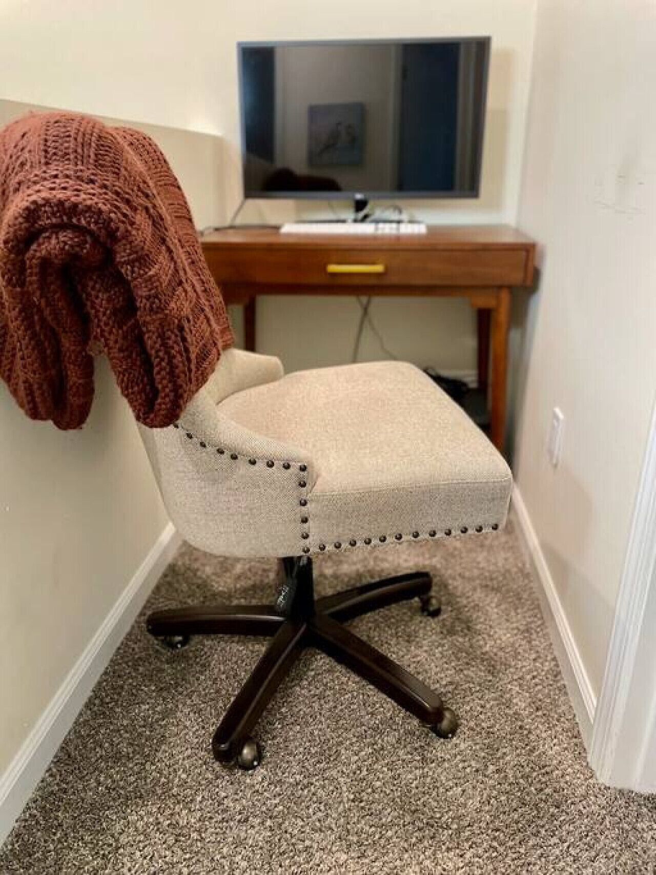 A small office space with a swivel chair, a desk, and a television.