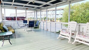 A covered outdoor seating area with tables and chairs, overlooking a body of water and a bridge. - CAPTAIN'S CAPTAIN-Waterfront House (Port Arthur)