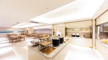 A modern hotel lobby with a reception desk, seating area, and a view of the sea.