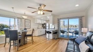 A modern apartment with a dining area, kitchen, and a balcony with a city view.