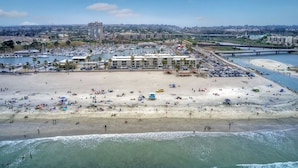 A beach with a marina, buildings, and a bridge.