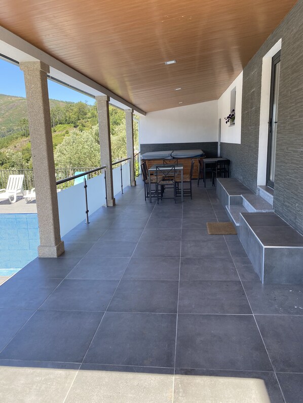 A covered outdoor area with a pool, a table with chairs, and a view of the surrounding landscape. - 7 Bedroom Villa in Vila Real (Vila Real)