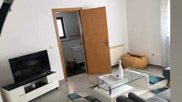 Un salon moderne avec un téléviseur à écran plat, une table basse en verre et un canapé.