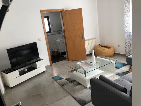 A modern living room with a flat-screen TV, glass coffee table, and a sofa. - 7 Bedroom Villa in Vila Real (Vila Real)
