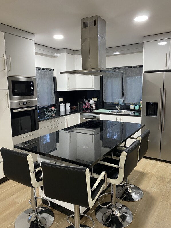 A modern kitchen with a central island, stainless steel appliances, and bar stools. - 7 Bedroom Villa in Vila Real (Vila Real)