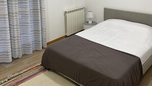 A bedroom with a bed, a radiator, a lamp, a painting on the wall, and a curtain. - 7 Bedroom Villa in Vila Real (Vila Real)