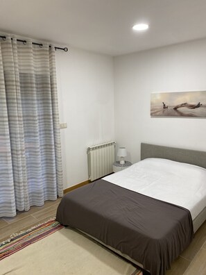 A bedroom with a bed, a radiator, a lamp, a painting on the wall, and a curtain. - 7 Bedroom Villa in Vila Real (Vila Real)