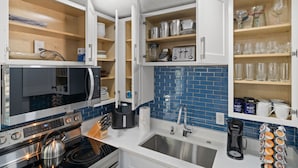Una cocina moderna con armarios blancos, microondas, estufa y lavaplatos.