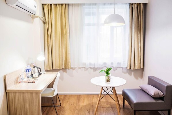 Una habitación de hotel con escritorio, silla, mesa redonda y sofá.