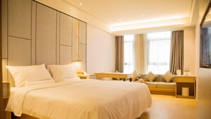 Una habitación de hotel moderna con una cama grande, un sofá, un escritorio y un televisor.