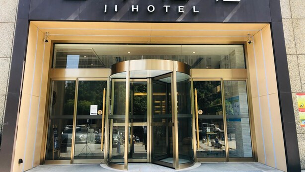 La entrada del Ji Hotel con una puerta giratoria y puertas de cristal.