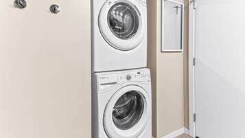 A laundry room with two stacked front-loading washing machines and a mirror on the wall.