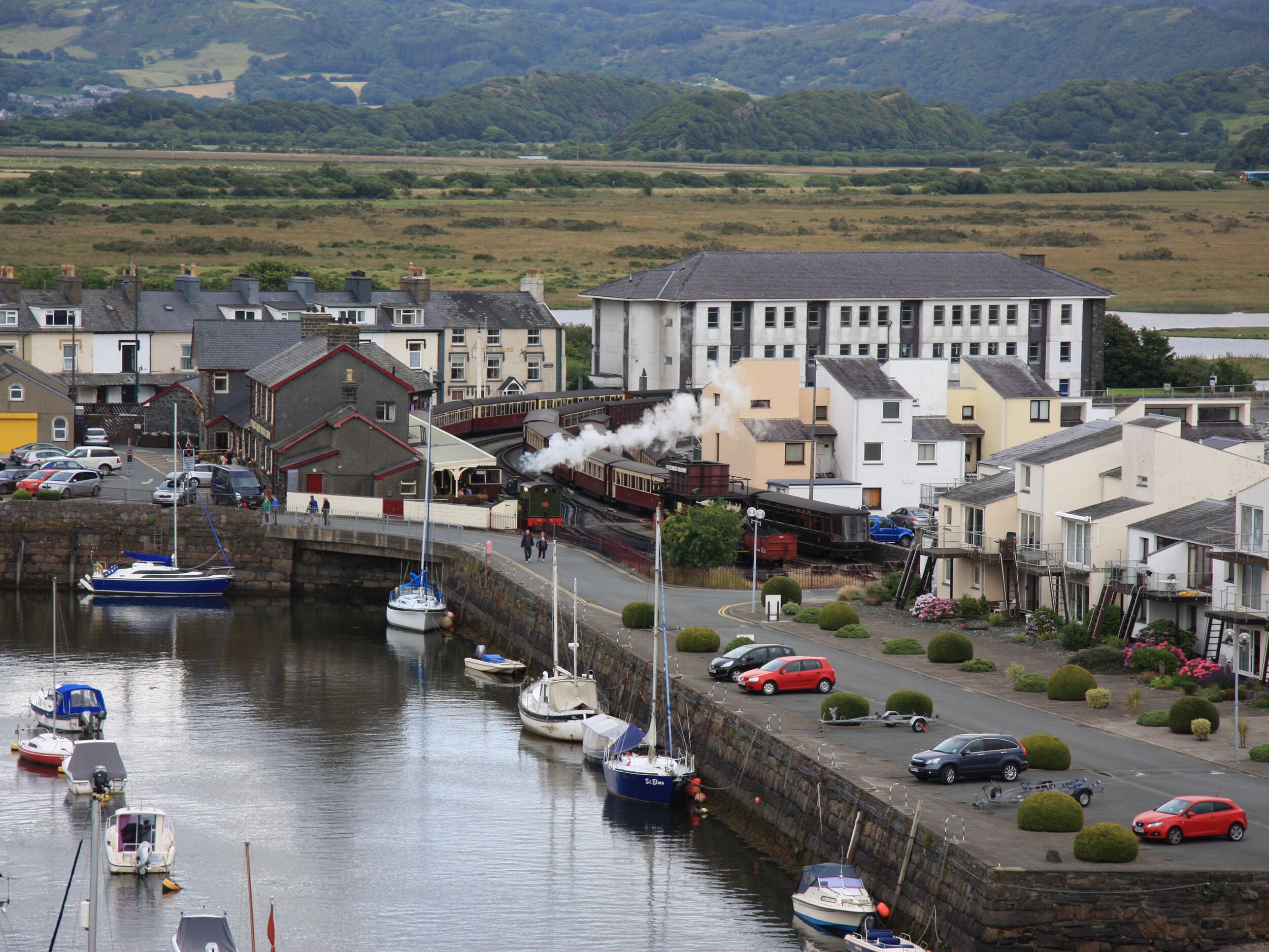 A harbor with boats, a train, and buildings along the waterfront.