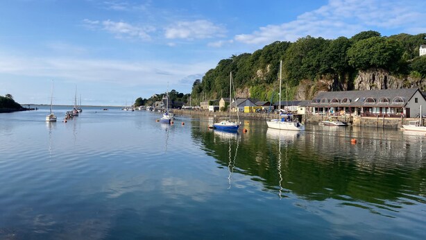 A harbor with boats, a building with a sloped roof, and a forested hillside. - 48A South Snowdon Wharf (Porthmadog)